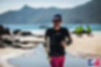 Man running on a sandy beach with mountains