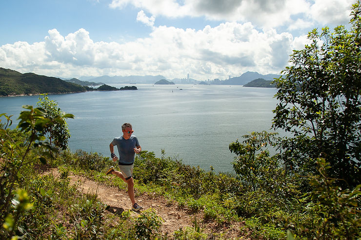 o Lodder running in the hills by the sea with Hong Kong skyline in the background – Resilience Keynote Speaker Hong Kong