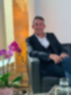 Smiling man in suit jacket sitting in armchair